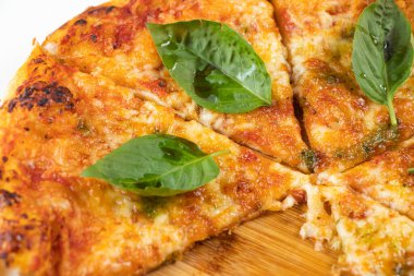 Klasik Margherita Pizza, domates sosu, mozzarella peyniri ve ahşap tahtada izole edilmiş fesleğen yaprakları beyaz arka planda yakın plan görüntüsü.