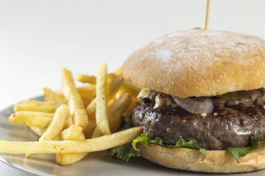 Beyaz arka planda izole edilmiş tabakta servis edilen klasik sığır etli burger Amerikan yemeğinin yakın plan görüntüsü.