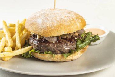 Kızarmış patates ve mayonezli klasik sığır burger. Beyaz arka planda, Amerikan fast food 'unun yakın plan görüntüsüne izole edilmiş olarak servis ediliyor.