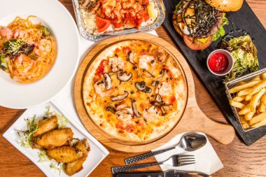 Siyah mantar, karidesli pizza, limonlu tavuk kanadı, İspanyol fırınlanmış domuz pirinci, Mentaiko karidesi ve Avokado spagettisi, güneşli tarafı, İtalyan yemeği masasının üstünde biftek köftesi.