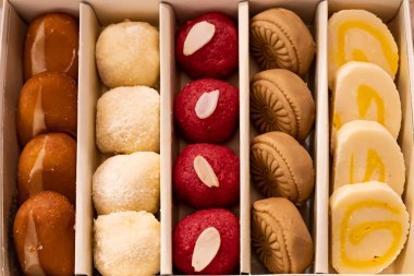 Assorted indian sweet box include Cream Gulab Jamun, Motichoor Laddu, GURER SONDESH, Cake Barfi, Balushai, Balushahi top view of pakistani and bangladeshi mithai dessert clipart