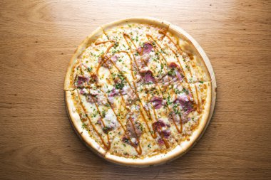 Mangal soslu domuz eti, barbekü sosu ve eritilmiş peynirle kaplı domuz eti pizzası İtalyan kuzeninin arka planında izole edilmiş tahta tahtada servis edildi.