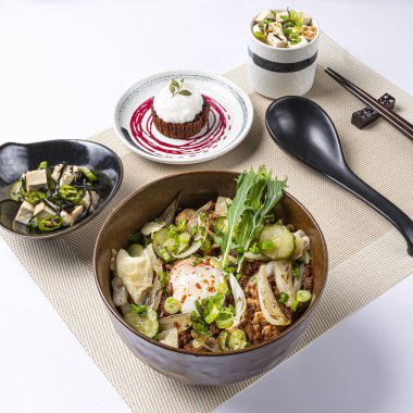 Wagyu Biftek Yanaklı Donburi üzerine soğan, yeşil soğan ve salatalıklı et suyu ve çikolatalı lava keki servis edilir. Peçete tarafında Japon yemeklerinin beyaz arka planda izole edilmiş hali.