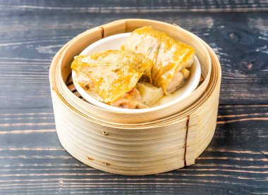 Buharda pişirilmiş mantarlı tavuk ayağı bambu buharlı tencereye sarılmış Hong Kong yemeğinin ahşap masa manzarasında izole edilmiş.