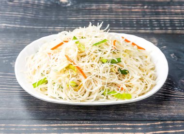 Çin usulü kızarmış pirinç eriştesi tepside servis edilir. Tahta masa kenarında Hong Kong yemeklerinin yanında.