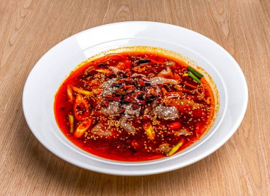 Sichuan baharatlı, kırmızı biberli, soğanlı ve susamlı biftek. Tahta masa başında Hong Kong yemeğinin yanında servis ediliyor.