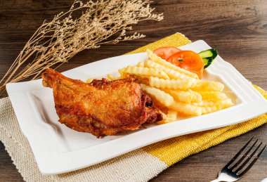 Kızarmış tavuk, patates kızartması ve salata tepside servis ediliyor. Peçete tarafında Hong Kong yemeğinin ahşap masada izole edilmiş hali.