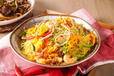 Xing Zhou Kızarmış Pirinç veya Singapur usulü Kızarmış Pirinç karides, sebze ve yumurta da dahil olmak üzere Hong Kong yemeklerinin ahşap arka planda izole edilmiş peçete tarafındaki kabın içinde servis edilir.