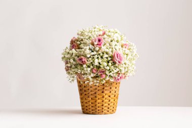 Hasır sepetin içinde pembe güller ve bebek nefesi sepetinde narin beyaz bebek nefesli çiçek aranjmanı gibi bulutlarla dolu beyaz arka plan manzarası çiçeklerin güzelliği.