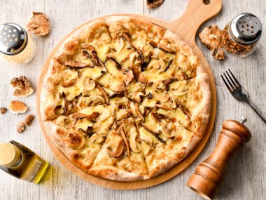 Mantar ve mantarlı pizza üzerine taze mantar, erimiş peynir ve ahşap tahtada servis edilen mantar yağı İtalya fast food manzarası.