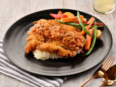 Pilav ve salatayla servis edilen tavuk parmigianası ahşap masa başında İtalyan fast food manzarası.