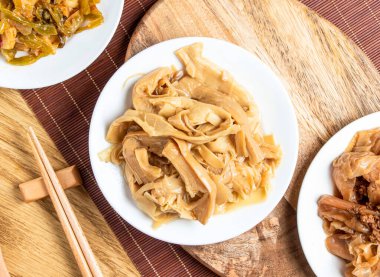 kaşık ve yemek çubuklarıyla servis edilen ağır ateşte pişirilmiş bambu filizleri tahtadan yapılmış Tayvan yemeklerinin üst görüntüsü.