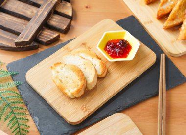 Ahşap tahtada, Tayvan yemeklerinin yanında çubuklarla servis edilen Fransız Kızarmış Ekmeği.