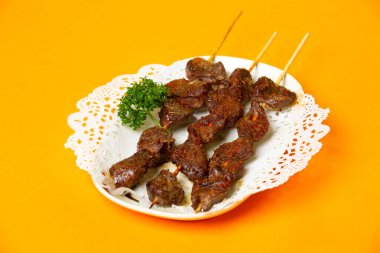 Izgara kuzu şiş tikka kebap portakal rengi arka plan görünümlü Hong Kong yemeği tabağında servis edilir.