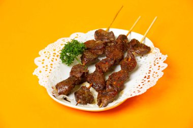 Izgara kuzu şiş tikka kebap portakal rengi arka plan görünümlü Hong Kong yemeği tabağında servis edilir.
