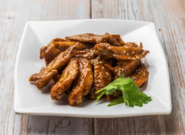 Ballı Tavuk Kanadı İpuçları, baharatlı sos, susam tohumu ve kişniş. Tahta Masa 'da servis edilen kişniş.