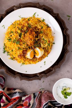 Chicken Biryani Rice with raita and boiled egg served in white plate on a decorative tray top view of Authentic Pakistani cuisine clipart