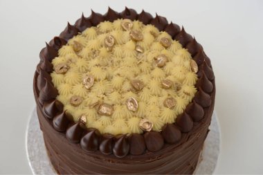 Dekoratif kremalı çikolatalı pasta. Çikolata ve krema katmanları. Kutlamalar için mükemmel taze, zarif bir pastanın yan görüntüsü.