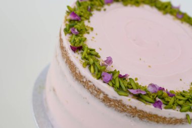 Çiçekli, şam fıstıklı ve gül yapraklı pasta. Yakından bakınca, kutlama için mükemmel bir pasta.