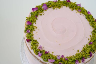 Çiçek desenli, şam fıstıklı ve gül yapraklı Pistachio Rose Pastası. Kutlamalar için mükemmel olan zarif pastanın üst görüntüsü.