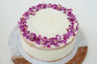 Dekoratif ahşap süslerle süslenmiş gül yaprağı ve gül yapraklı pasta. Kutlamalar için mükemmel olan zarif pastanın yan görüntüsü.