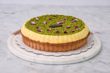 Fıstık ezmeli turta, kremalı, şam fıstıklı, gül yapraklarıyla süslenmiş ve çikolatalı, lezzetli fırında pişmiş tatlı manzaralı.