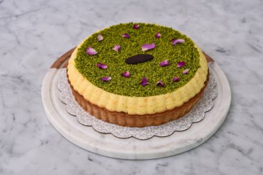 Fıstık ezmeli turta, kremalı, şam fıstığı soslu, gül yapraklarıyla süslenmiş ve çikolata parçalı, lezzetli fırında pişirilmiş tatlı manzaralı.