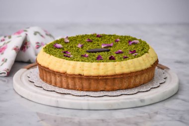 Fıstık ezmeli turta, kremalı, şam fıstıklı, gül yapraklarıyla süslenmiş ve peçeteli, lezzetli, fırında pişmiş tatlı manzaralı çikolata parçalı.