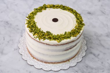 Zarif Pistachio Kek Görünür pasta katmanları ve pürüzsüz beyaz krema ile süslenmiş Gri arkaplan manzaralı fıstıklı lezzetli tatlı