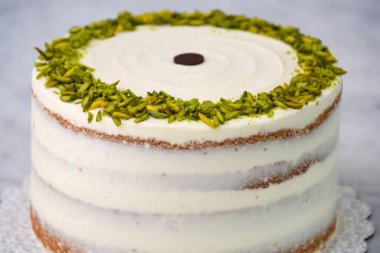 Zarif Pistachio Kek Görünür pasta katmanları ve pürüzsüz beyaz krema ile süslenmiş Gri arkaplan üzerinde şam fıstığı