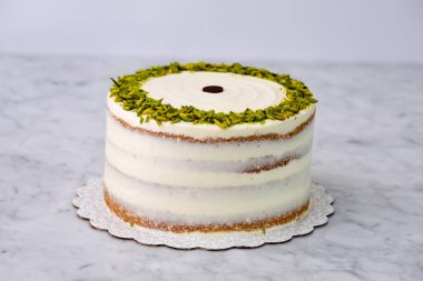 Zarif Pistachio Kek Görünür pasta katmanları ve pürüzsüz beyaz bir süsleme kenarlarında şam fıstığı ile süslenmiş lezzetli tatlı arkaplan manzarası