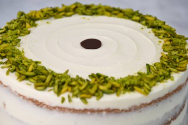 Zarif Pistachio Pastası Görünür pasta katmanları ve kenarlarında doğranmış şam fıstığı ile süslenmiş pürüzsüz beyaz krema lezzetli tatlı manzarası