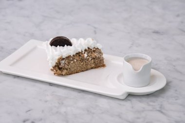 Kremalı Oreo Pastası. Ezilmiş çikolatalı sandviç kurabiyeleriyle. Üstünde krema ve süt sosu var.