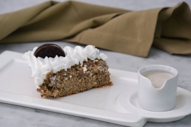 Kremalı Oreo Pastası, ezilmiş çikolatalı sandviç kurabiyeleriyle, üstüne krem şanti ve sütle servis edilmiş peçeteyle servis edilmiş, arka planda izole edilmiş tatlı.