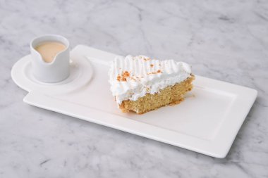 Kremalı Tres Leches Pastası. Süt soslu dilimlenmiş krema. Tepside servis ediliyor.