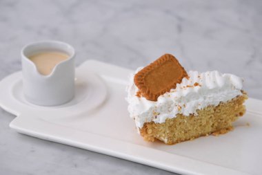 Biscoff Tres Sülükleri Süt Sosu ile dilimlenmiş krema tepside servis edilir gri arka planda izole edilmiş klasik ve hoşgörülü tatlıya yakın görünüm