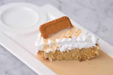 Biscoff Tres Sülükleri Süt Sosu ile dilimlenmiş kek tepside servis edilen krema gri arka planda izole edilmiş tatlı manzarası
