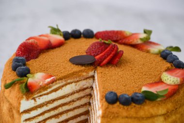 Çilekli ve yabanmersini dilimli katmanlı Medovik Bal Keki. Gri arka planda klasik lezzetli kafe tatlısının yakın plan görüntüsü.