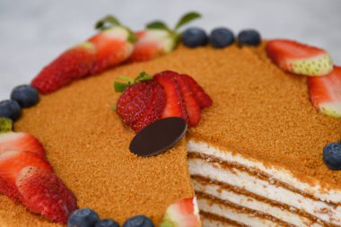 Çilekli ve yabanmersinli katmanlı Medovik Bal Keki. Gri arka planda izole edilmiş klasik lezzetli kafe tatlısının yakın plan görüntüsü.