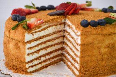 Çilekli ve yaban mersinli katmanlı Medovik Bal Keki. Gri arka planda izole edilmiş. Klasik lezzetli kafe tatlısının yakın plan görüntüsü.