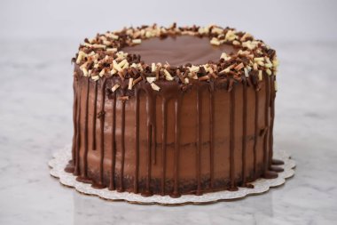 Çikolata parçacıklı zengin çikolatalı pasta. Yumuşak çikolata parçacıkları ile kaplı. Arka planda izole edilmiş çikolata kafe tatlısına güzel bir şekilde damlıyor.