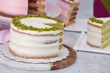 Şam fıstıklı ve ahududulu kekler ve Rose Butter kremalı dilimler, pembe ve beyaz kaplama zarif tatlıların yan görüntüsü