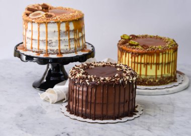 Karamelli incir, fıstıklı karamel ve peçeteli çikolatalı pasta gibi çeşitli gurme pastalar.