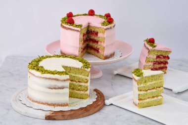 Şam fıstıklı ve ahududulu kekler ve Rose Butter kremalı dilimler, zarif tatlıların pembe ve beyaz kremalı yan görünüşü