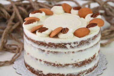Lezzetli havuçlu kek, fındıklı süslemeler, krem peynirle kaplanmış baharatlı pasta, krem peynirli krema, yakın plan, klasik ve lezzetli kafe pastası.