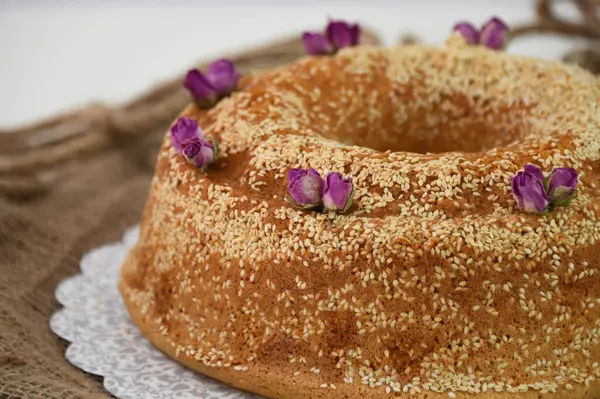 Zarif lavantalı kek, pudra şekeriyle hafifçe tozlanmış ve üzerine beyaz jöle serpiştirilmiş ve susam tohumları serpiştirilmiş klasik tatlıya yakın.