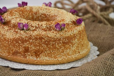 Zarif lavantalı kek, pudra şekeriyle hafifçe tozlanmış ve üzerine beyaz jöle serpiştirilmiş ve susam tohumları serpiştirilmiş klasik tatlı görüntüsü.