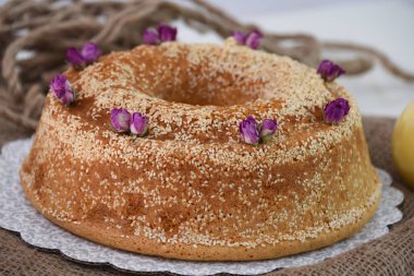 Zarif lavantalı kek, pudra şekeriyle hafifçe tozlanmış ve üzerine beyaz jöle serpiştirilmiş ve peçeteye izole edilmiş susam tohumları serpiştirilmiş eşsiz fırınlanmış tatlı.