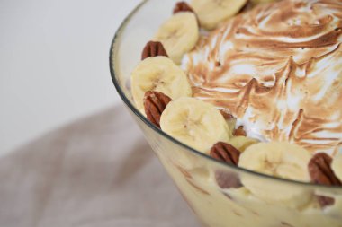 Kremalı muzlu puding şeffaf cam bardakta tatlılar kremalı vanilyalı puding, taze muz dilimleri peçeteye izole edilmiş tatlı kafe manzarası