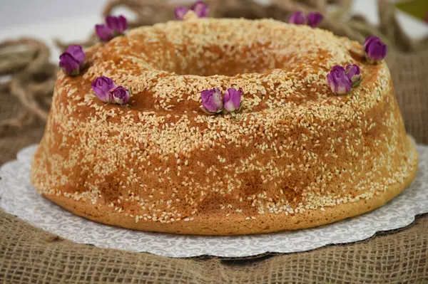 Zarif lavantalı kek, pudra şekerle hafifçe tozlanmış ve üzerine beyaz jöle serpiştirilmiş ve susam tohumlu fırında pişmiş kafe tatlı.